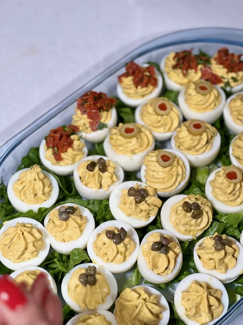 Tray of deviled eggs with varied garnishes
