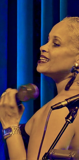 Malika performing with a microphone on stage